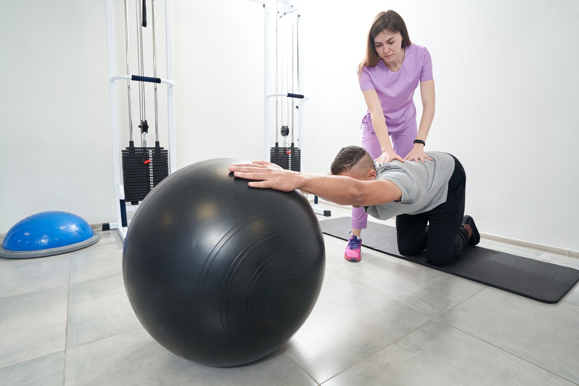 man-doing-rehabilitation-exercise-with-gym-ball-in-clinic
